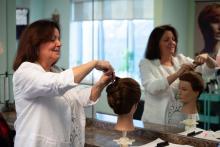 shallow creek academy of hair design hairstylist teacher instructor giving an updo hairstyle demonstration on a mannequin hairstyling college diploma near me in brantford ontario skilled trades ontario